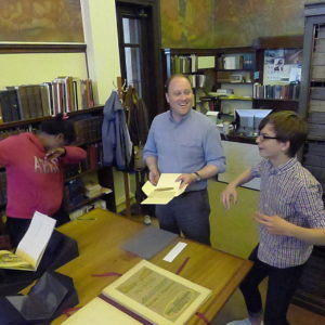Jordan Goffin, Head Curator of Special Collections, and two students looking at items in Special Collections.