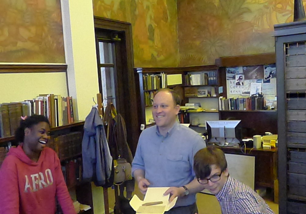 Jordan Goffin, Head Curator of Special Collections, and two students looking at items in Special Collections