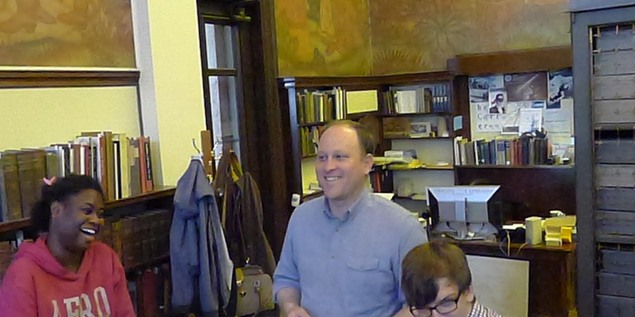 Jordan Goffin, Head Curator of Special Collections, and two students looking at items in Special Collections