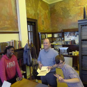 Jordan Goffin, Head Curator of Special Collections, and two students looking at items in Special Collections