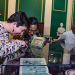 People looking in cases at the On The Table exhibition opening at Providence Public Library