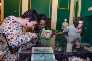 People looking in cases at the On The Table exhibition opening at Providence Public Library