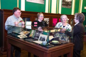 People looking in cases at the On The Table exhibition opening at Providence Public Library