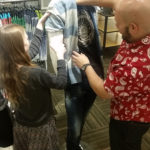 A visual merchandiser and a Teen Squad participant dress a mannequin