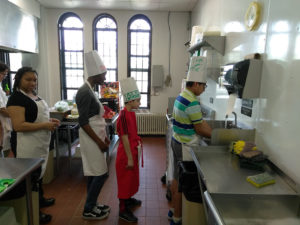 Teens wearing chef hats washing their hands in a kitchen