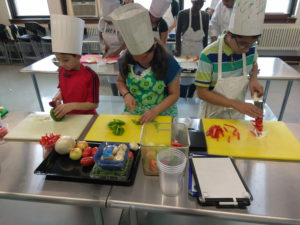 Teen Squad culinary arts program participants dice red and green peppers in a kitchen