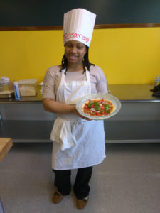 A Teen Squad participant holding a dish she prepared as part of the culinary arts program