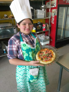 A Teen Squad member holding up a quiche she prepared as part of the culinary arts program
