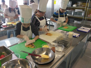 Teen Squad members chopping ingredients in a kitchen as part of the culinary arts program