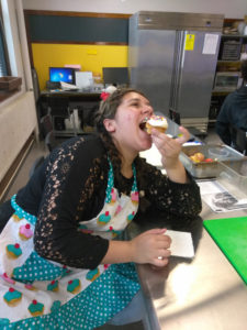 A Teen Squad member eats a cupcake in a kitchen