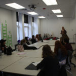 Teen Squad members listen to a mentor discuss dress design