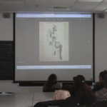 Teens look at a slide projected illustration of people in 1920s dress