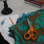 Brown and teal colored fabric near a sketch of 1920s flapper style dresses