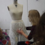 A mentor displays a dress form with a slip on it to members of the Teen Squad
