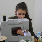 A Teen Squad member sews purple fabric on a sewing machine