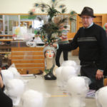 A mentor displaying an elaborate peacock headdress on a mannequin head