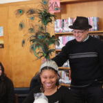 A Teen Squad member trying on an elaborate peacock headdress with the help of a mentor