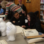 Teen Squad members discuss reference material they are using to design their headdresses