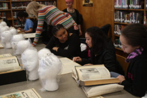 Teen Squad members discuss reference material they are using to design their headdresses