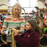 A mentor and a Teen Squad member discuss a headdress in progress