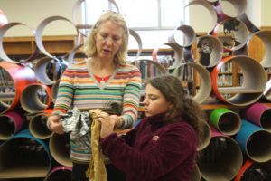 A mentor and a Teen Squad member discuss a headdress in progress