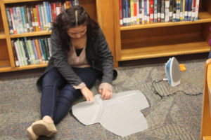 A Teen Squad participant uses an iron to prepare fabric