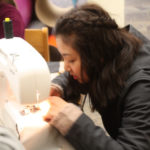 A Teen Squad member uses a sewing machine to sew fabric