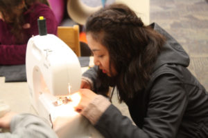 A Teen Squad member uses a sewing machine to sew fabric