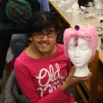 A Teen Squad member holds a mannequin head with a pink headdress on it