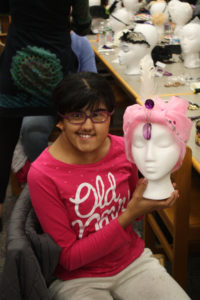 A Teen Squad member holds a mannequin head with a pink headdress on it