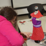 A Teen Squad member prepares a dress on a miniature dress form