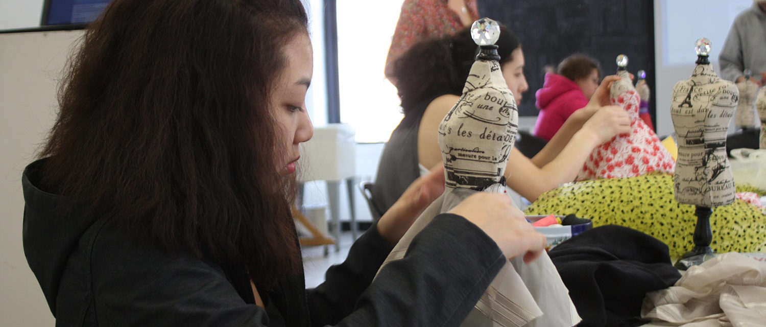 A Teen Squad member prepares a dress on a miniature dress form