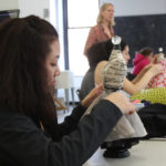 A Teen Squad member prepares a dress on a miniature dress form