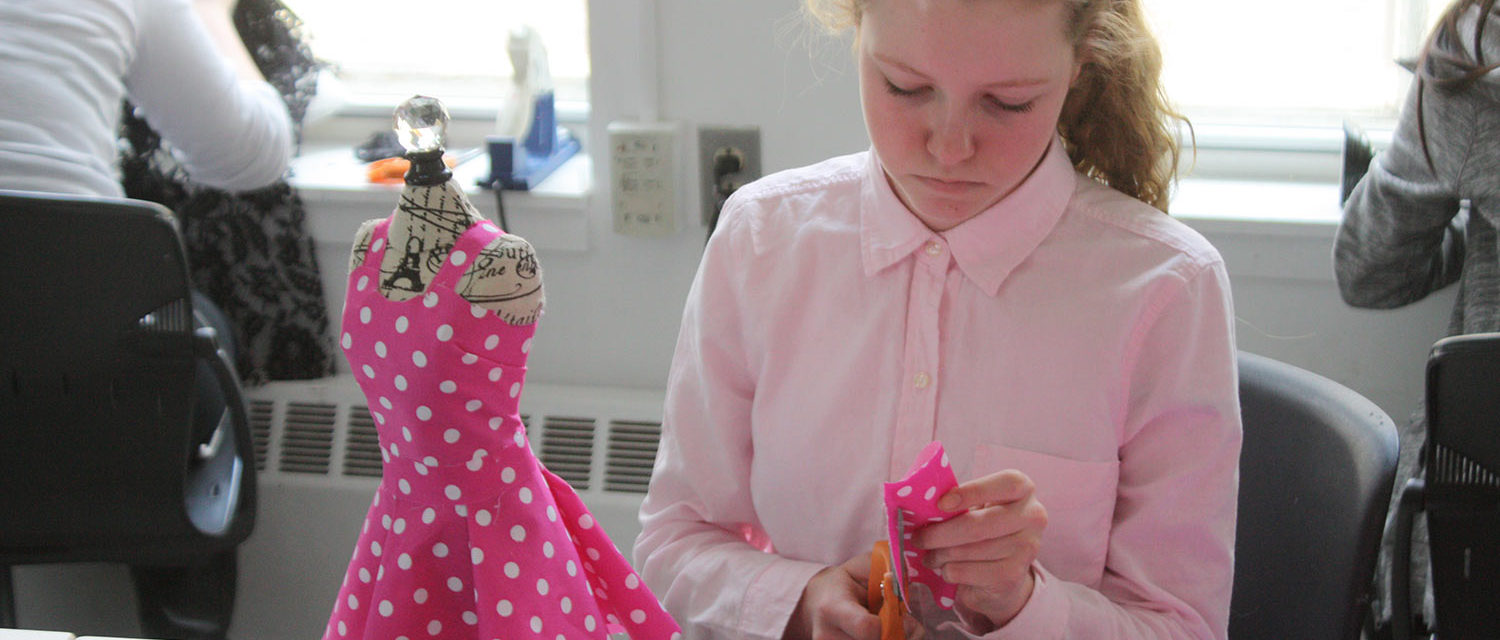 A teen squad member cuts pink polka dot fabric