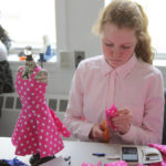 A teen squad member cuts pink polka dot fabric