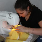 A Teen Squad member sews fabric using a sewing machine