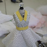 A miniature dress form with a black and white polka dress on it.