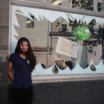 A Teen Squad member posing with a window display at Providence Public Library